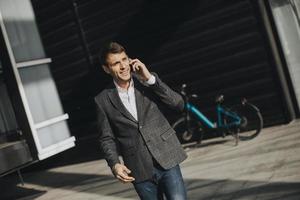 Young businessman walking away from the ebike and using mobile phone photo