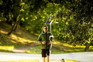 Athletic young man running while doing workout in sunny green park photo