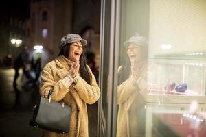 Beautiful young woman by the shop window at Christmas time photo