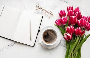cuaderno, taza de café y tulipanes rosas foto