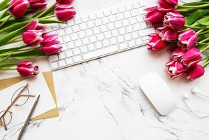 espacio de trabajo con teclado y tulipanes foto