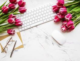 espacio de trabajo con teclado y tulipanes foto