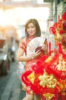 Mujer asiática vistiendo ropa de tradición china con ventilador de bambú chino toothy cara sonriente en la calle yaowarat, la ciudad china de Bangkok, Tailandia foto