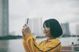 asian teenager raising mobile phone and looking into device screen