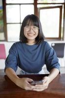 asian teenager toothy smiling with happiness and holding mobilephone in hand photo