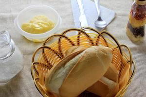 Cerrar el pan francés en la mesa del desayuno con mantequilla y cubiertos foto