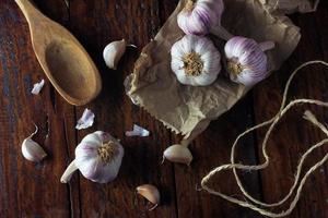 Garlic bulbs on packing paper, on rustic wooden table. Closeup of garlic photo