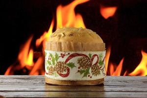 panettone, decorative food, on wooden table, fire in the background photo