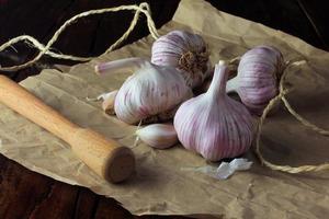 Garlic bulbs on packing paper, on rustic wooden table. Closeup garlic photo