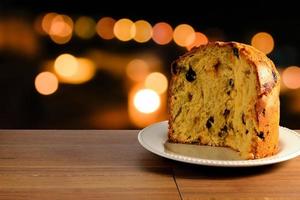 closeup panettone on ceramic plate on wooden table, bokeh background with lights photo