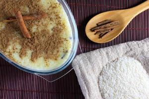 rice pudding with cinnamon in glass container over bamboo towel, rice over sack photo