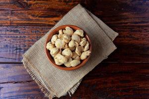 Soybeans meat, chunks in a brown ceramic bowl. Raw soybeans chunks on rustic wooden background photo