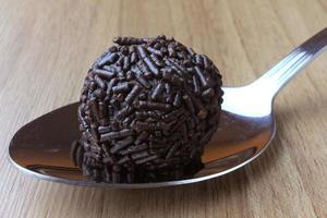 brigadeiro, brigadier, chocolate dulce típico de la cocina brasileña cubierto de partículas, sobre un fondo de madera. foto