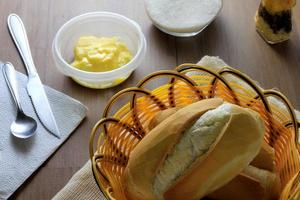 Cerrar el pan francés en la mesa de desayuno de madera con mantequilla y cubiertos foto