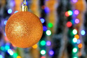 Golden hanging ball, christmas decoration with blurred lights background.