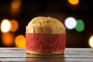 panettone, decorative food, on wooden table, blurred lights in the background photo