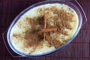 rice pudding with cinnamon in glass bowl on bamboo tablecloth, next wooden spoon photo