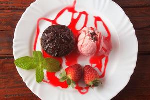 petit gateau with ice cream on white plate with strawberry over rustic wooden table photo