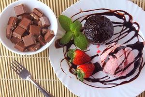 petit gateau with ice cream on white plate with strawberry over rustic wooden table photo