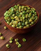 Salted green peas in wooden bowl on the table, Healthy snack, Vegetarian food photo