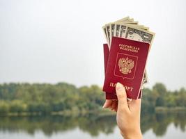 A foreign passport and dollars in your hand, against the background of nature.