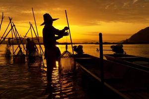 La silueta de los pescadores que trabajan en la hora dorada del amanecer en el río Mekong entre Tailandia y Laos foto