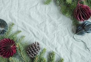 Spruce twigs with paper decorations on the green linen crumpled textile background