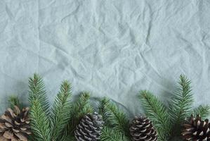 Spruce twigs on the green linen crumpled textile background photo