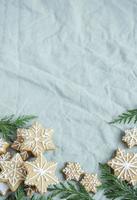 Spruce twigs with Christmas gingerbread cookies on the green linen crumpled textile background photo