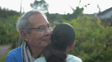 Happy senior grandfather in eyeglasses embracing his young granddaughter.