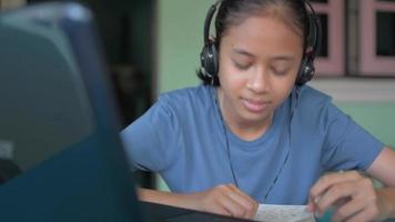 High school girl wear headphones watching online webcasting class on laptop at home. video