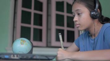 tienermeisje die hoofdtelefoon draagt die les online van laptop thuis studeert. video