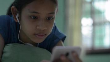 adolescente deitada na cama desfrutar de mensagens de texto na comunicação social online de smartphone. video