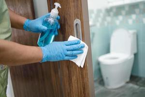 limpiar la manija del inodoro de la puerta en el inodoro con alcohol y pañuelos en la oficina y el hogar para proteger el coronavirus covid 19 foto