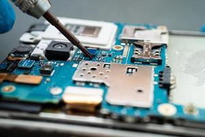 Technician repairing inside of mobile phone by soldering iron. Integrated Circuit. the concept of data, hardware, technology. photo