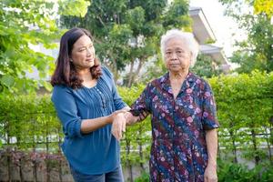 Asian elderly woman with caregiver walking with happy in nature park. photo