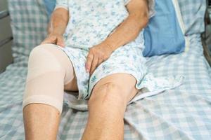 Paciente asiático mayor o mayor de la mujer de la señora mayor con la articulación del dolor del soporte de la rodilla en la cama en la sala del hospital de enfermería, concepto médico fuerte y saludable.