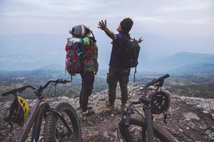 Asian lover women and men Travel Nature. Travel relax ride a bike Wilderness in the wild. Standing on a rocky cliff. Thailand photo