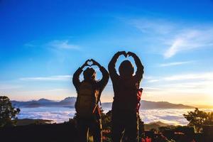 Lover women and men asians travel relax in the holiday. Stand up for sunrise on the Moutain,happy honeymoon,Raised his hand to make a heart shape. photo