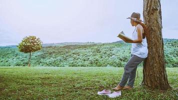 Asian women relax in the holiday. Stand read books on grassland in the park. photo