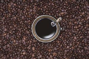 Cup of Black coffee placed, with Roasted Full frame coffee beans background photo