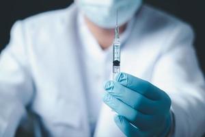 Doctor or scientist in laboratory holding a syringe with liquid vaccines for children or older adults, Concept diseases,medical care,science. photo