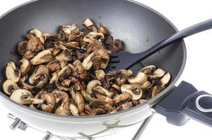 Sliced champignons fried in pan isolated on white background. photo