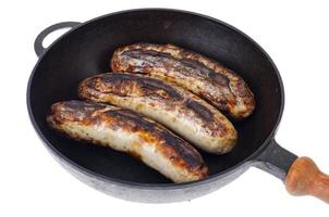 Cast iron pan with grilled sausages on white background photo