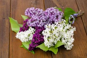 Flowering branches of lilac on wooden surface photo
