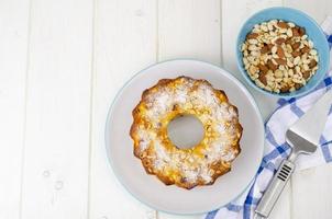 Golden homemade muffin with nuts on white wooden table, napkin. photo