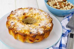 Golden homemade muffin with nuts on white wooden table, napkin. photo