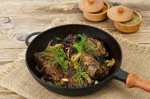 Cast-iron frying pan on wooden table with fried liver. photo