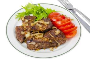 Pieces of fried liver with onions, fresh leaves of salads photo