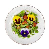 Vegetable salad with edible flowers on white background. photo